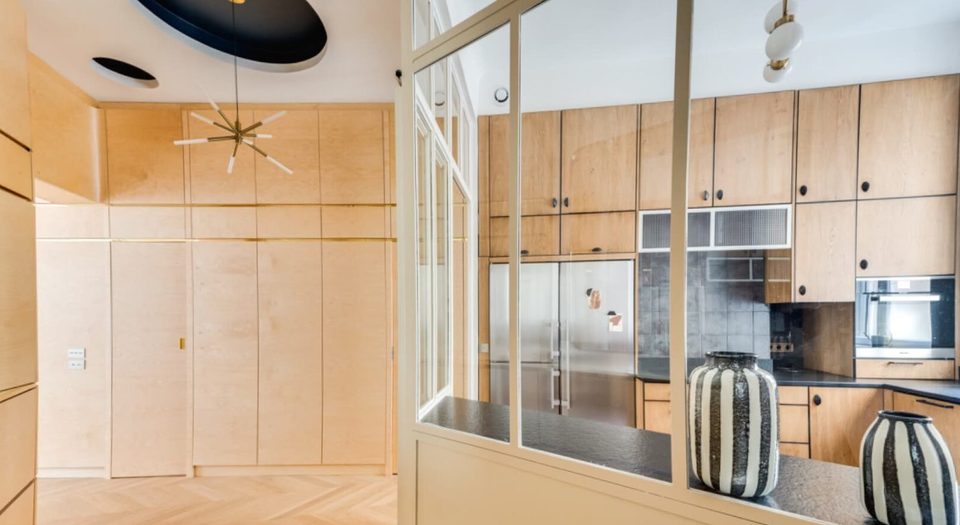 Atelier verrière in steel and glass opening onto the oak kitchen with stainless appliances