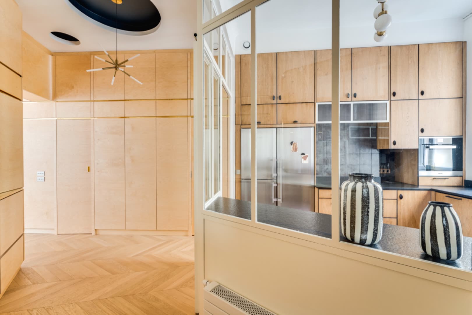 Steel-and-glass verrière — atelier-style partition between entry and kitchen