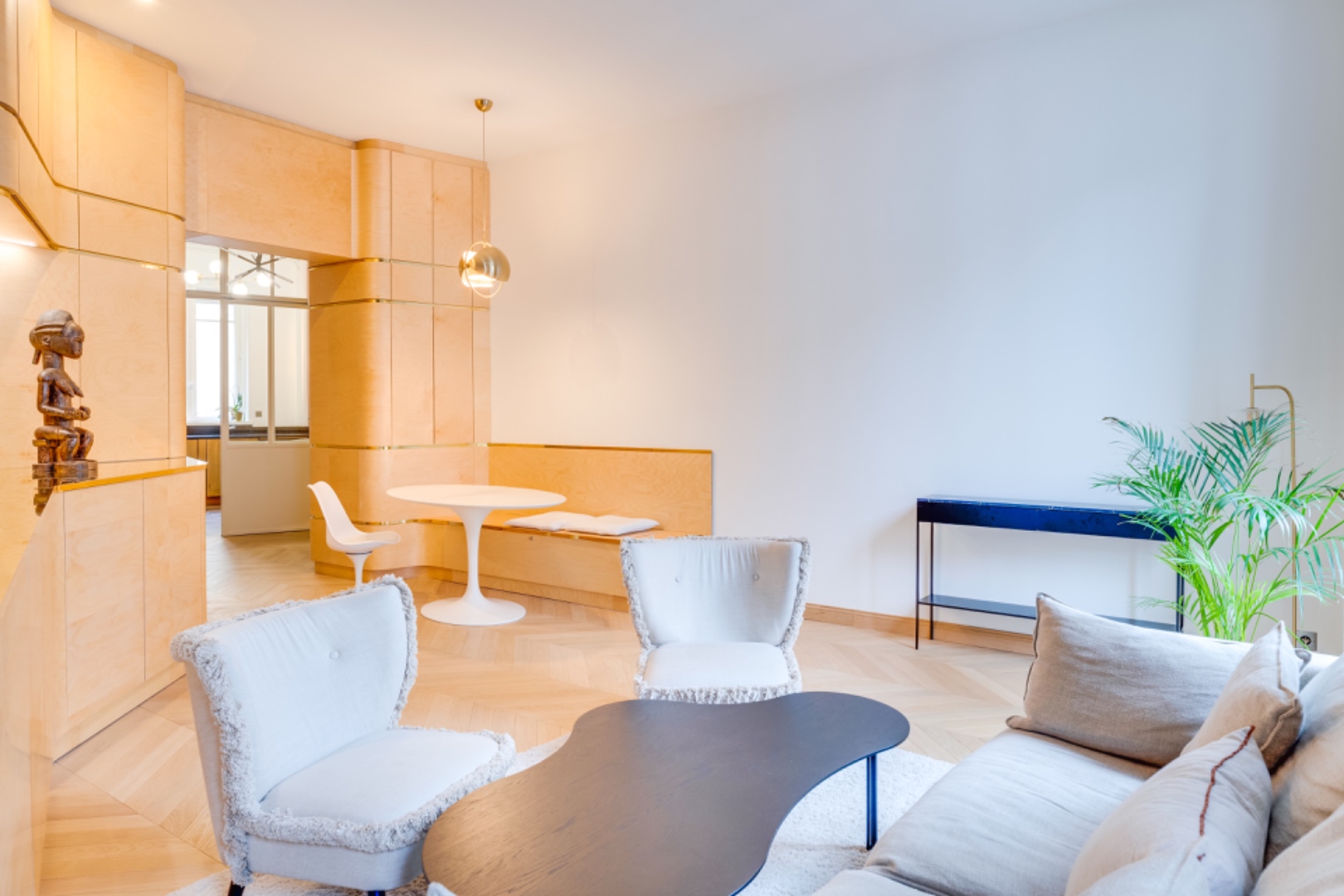 Open salon with herringbone parquet, custom millwork and Saarinen-style table